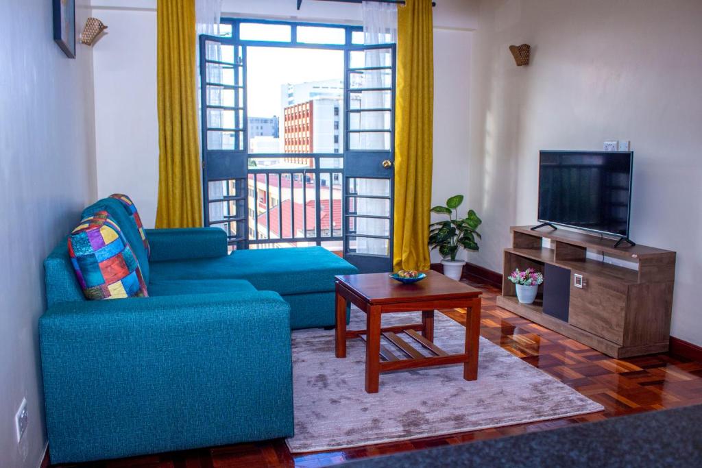 a living room with a blue couch and a television at Kasty M Apartments- W Place in Nairobi