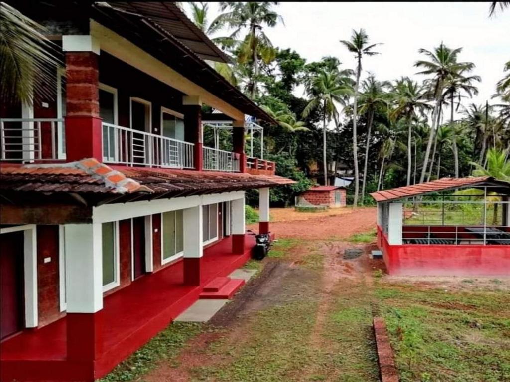 a red and white house with trees in the background at kannur west beach homestay in Kannur