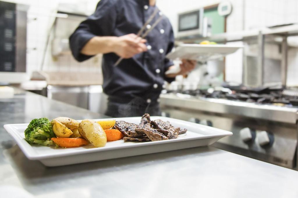 a person in a kitchen preparing a plate of food at Hotel Stadt Berlin in Jessen