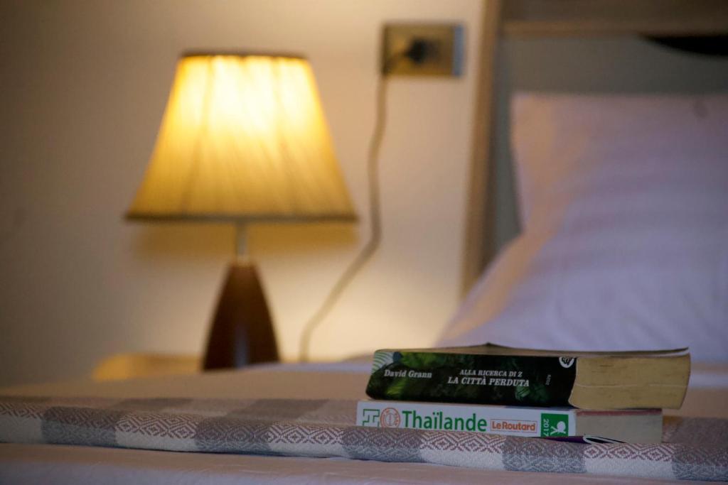 una pila de libros sentados en una cama con una lámpara en Gecko Lipe Resort en Ko Lipe