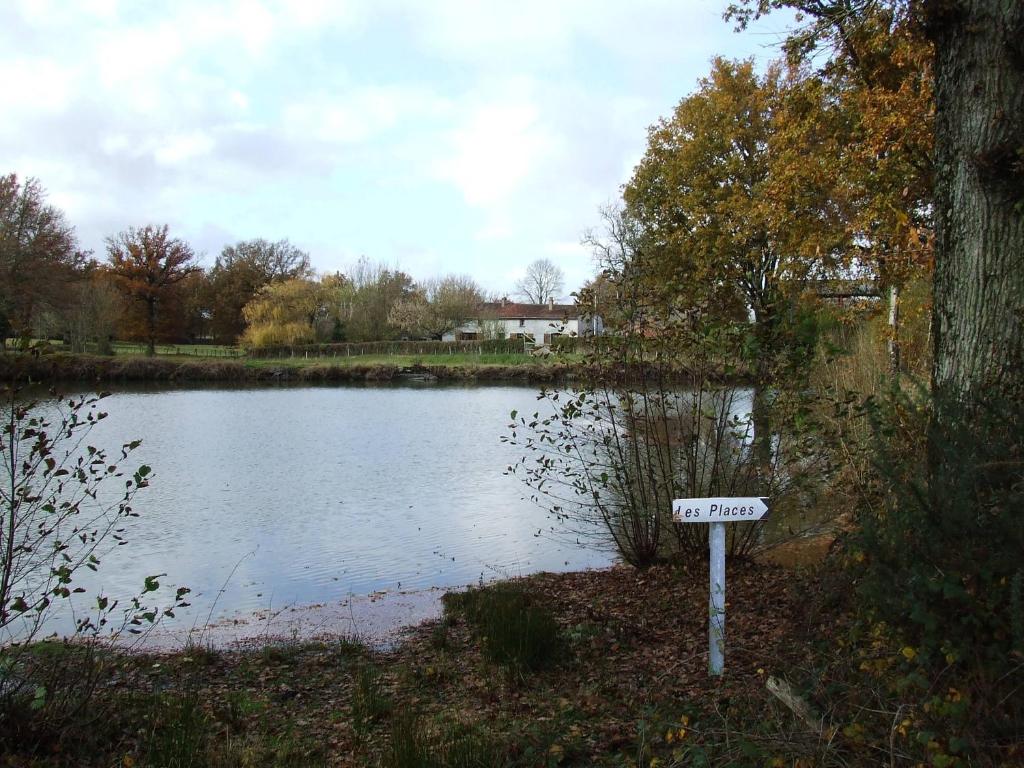 una señal frente a un estanque con una casa en Gite à la ferme Les places, en La Chapelle-Bertrand