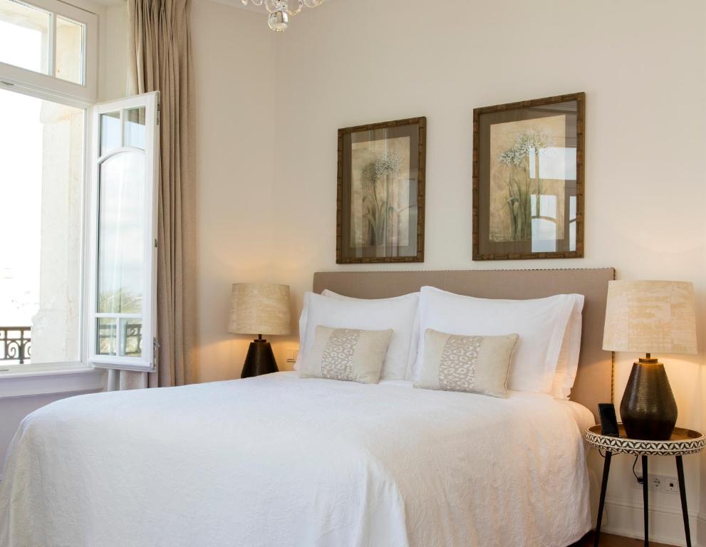 a bedroom with a white bed with two lamps at Grand House - Relais & Chateaux in Vila Real de Santo António