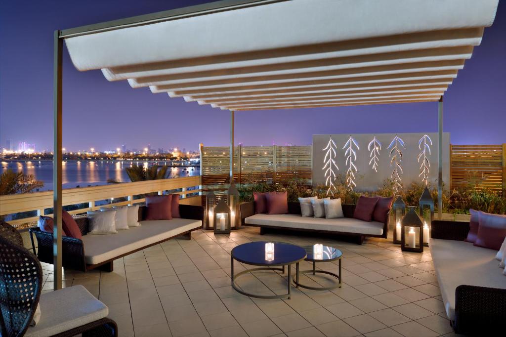a rooftop patio with couches and a view of the water at Mövenpick Hotel Bahrain in Manama