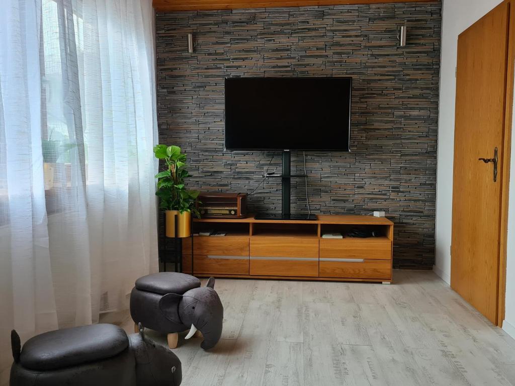 a living room with a television on a brick wall at Ferienwohnung Krähennest in den Hegaubergen - Nähe Bodensee in Mühlhausen-Ehingen