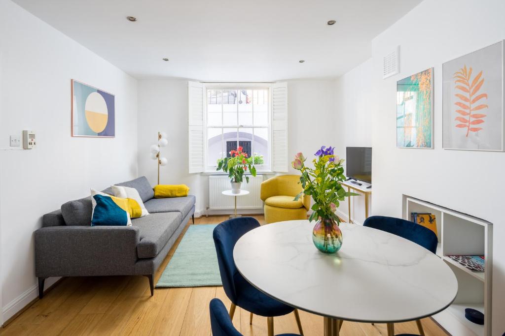 ein Wohnzimmer mit einem Sofa und einem Tisch in der Unterkunft Chic and modern 2-bed flat with patio in Pimlico, Central London in London
