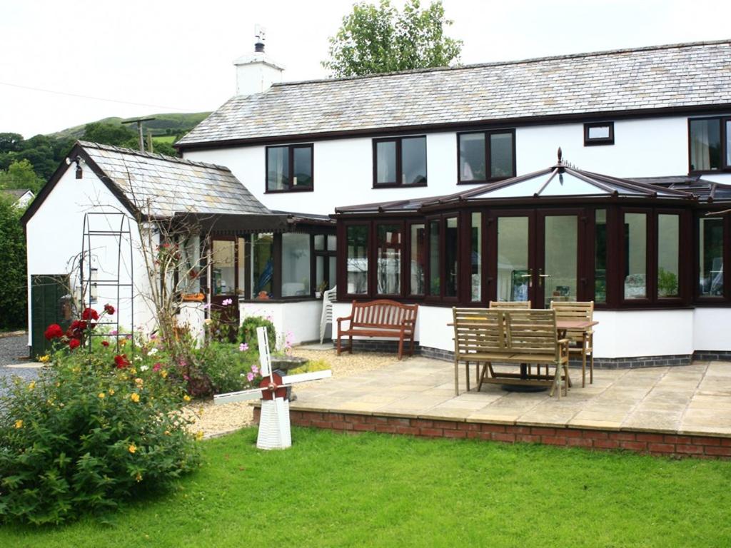 a white house with a patio and a bench at The Old School House Bed and Breakfast in Llanbrynmair