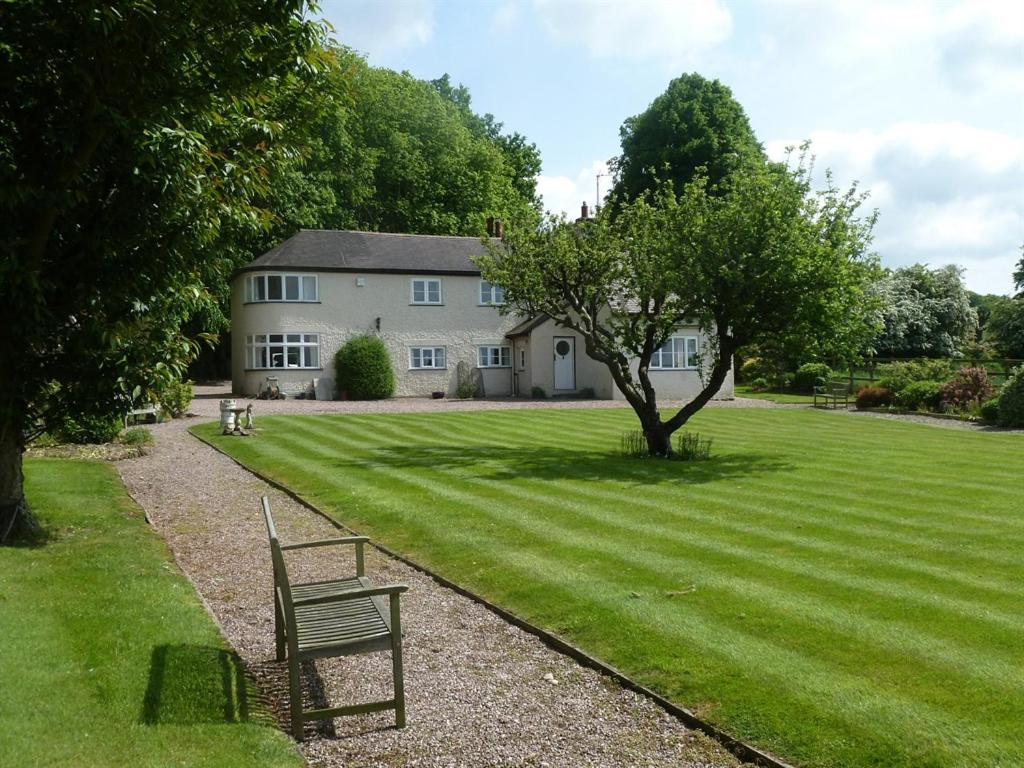 eine Bank, die im Gras vor einem Haus sitzt in der Unterkunft The Coach House in Milford