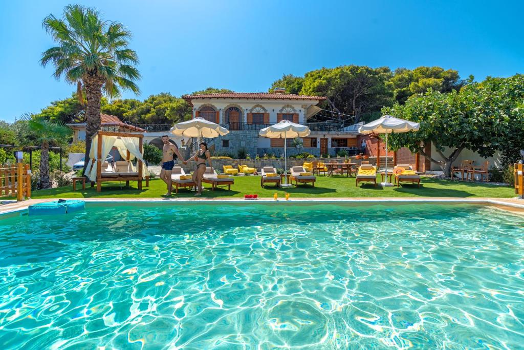 una gran piscina con sillas y sombrillas en Villa Artemida Vravrona en Vravrona