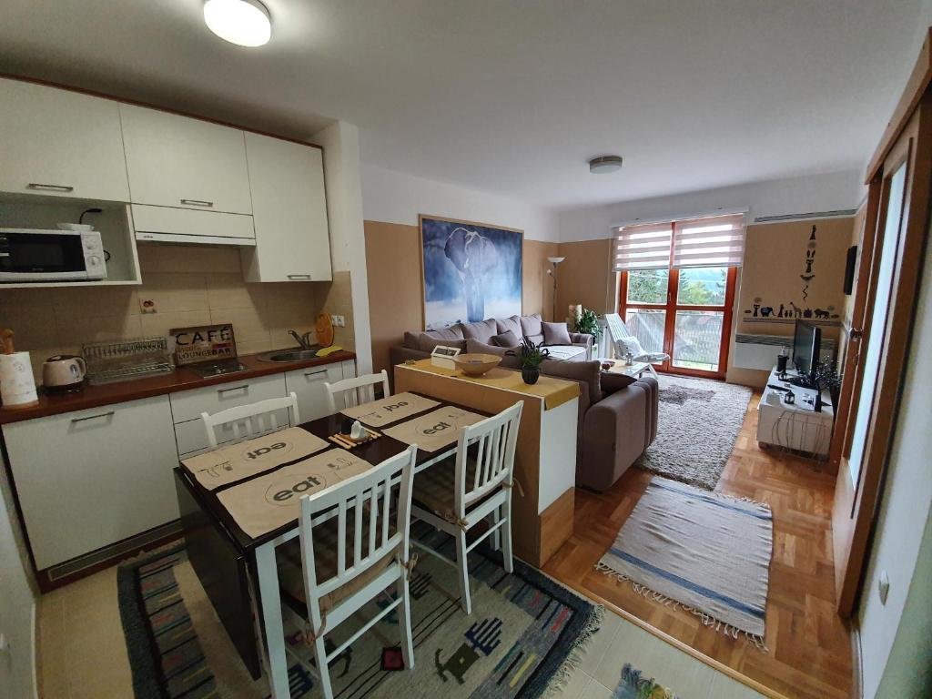 Una cocina y una sala de estar con mesa y sillas. en Apartman Lari, en Vlašić