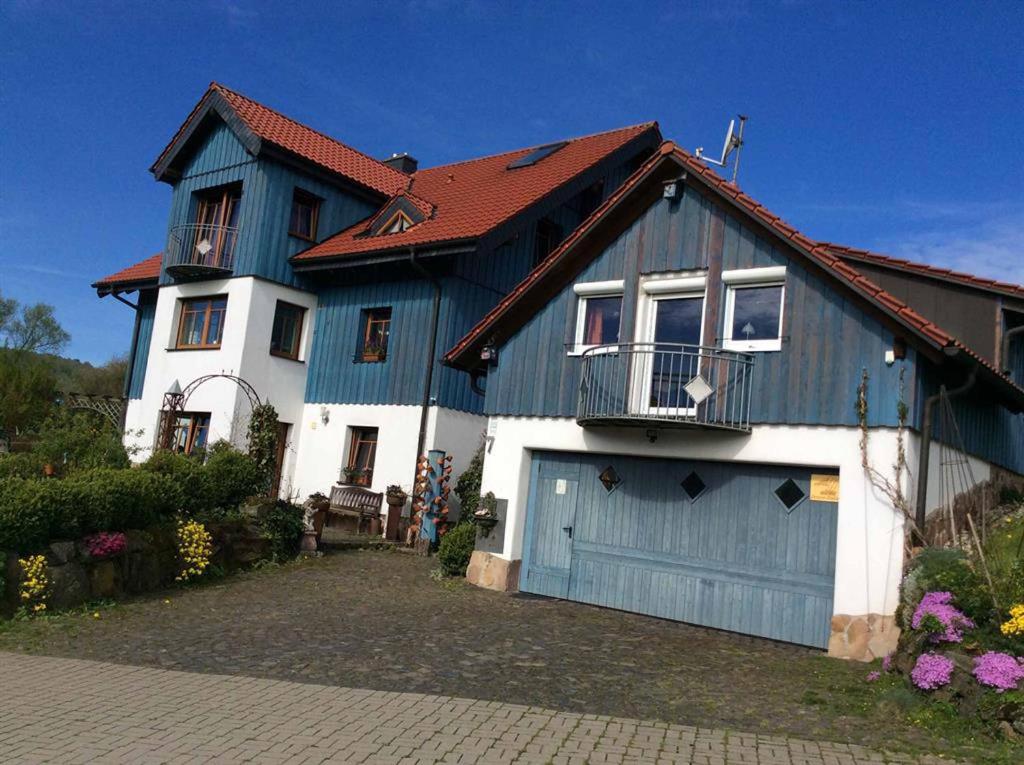 una casa azul y blanca con garaje en Ferienwohnung Stirnbergblick, en Ehrenberg