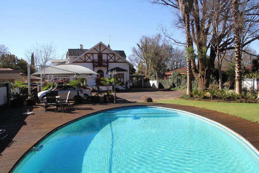 a large blue swimming pool in front of a house at The Oak Potch Guesthouse in Potchefstroom