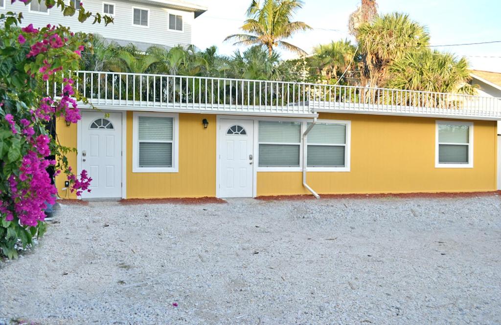 a yellow house with white doors and flowers at Siesta Key Beach - Bari 665 #2 in Siesta Key
