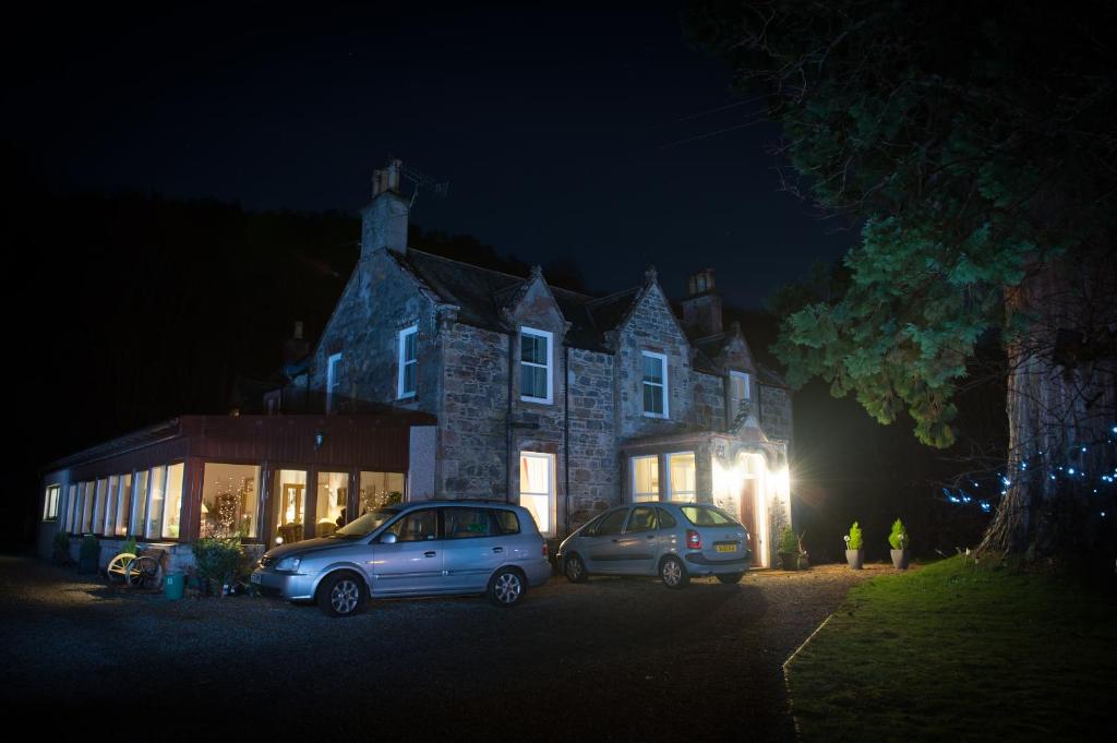 dos autos estacionados frente a un edificio por la noche en Kilmichael House en Drumnadrochit