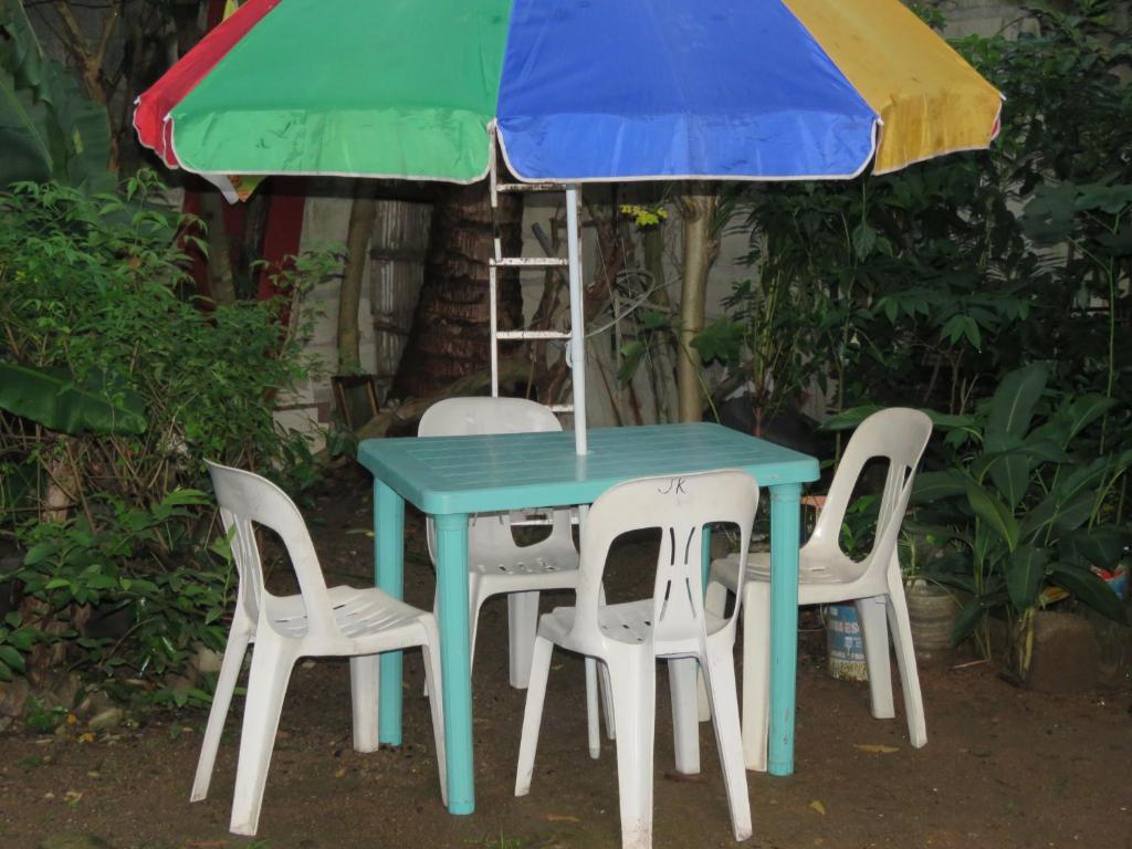 a table with four chairs and an umbrella at Perlies Inn Balcony House in Tanay