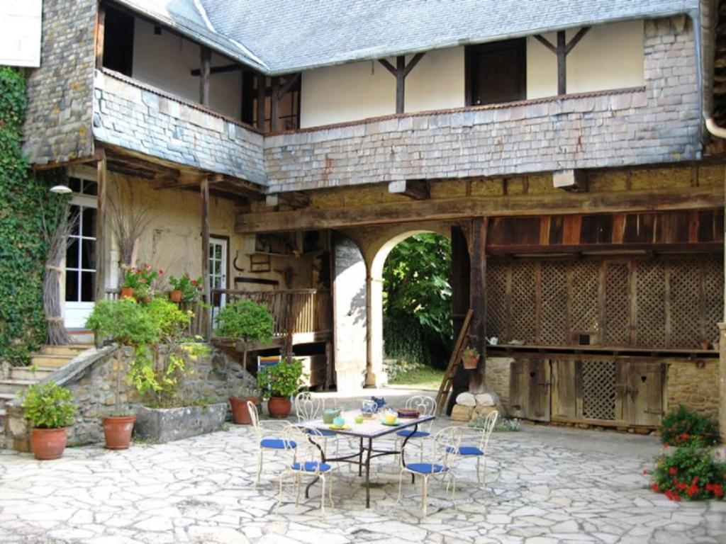 um pátio com uma mesa e cadeiras em frente a um edifício em La Ferme Dagué em Lasseube