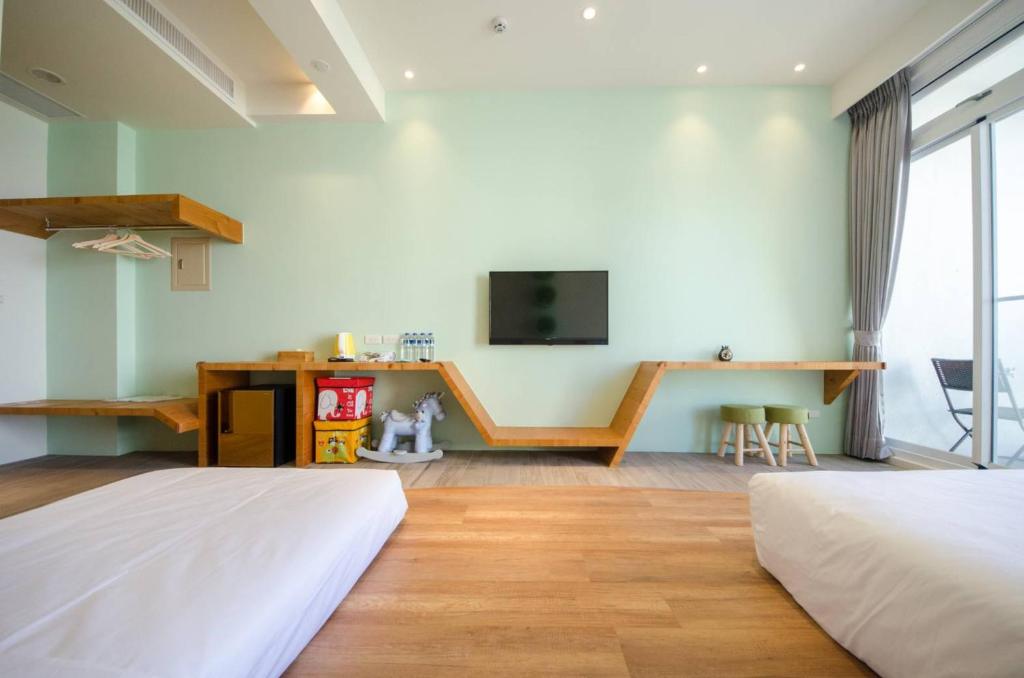 a bedroom with two beds and a tv on the wall at 墾丁山風足跡 in Kenting