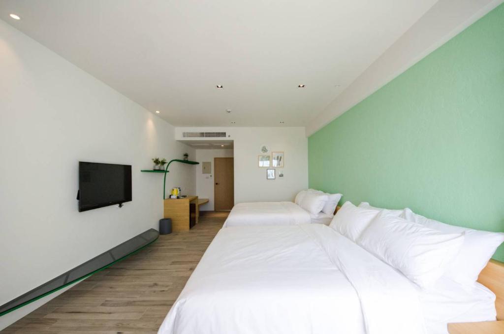 a bedroom with two beds and a flat screen tv at 墾丁山風足跡 in Kenting