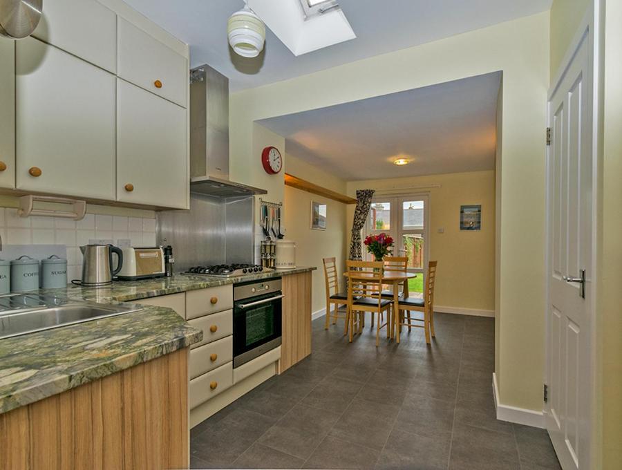 a kitchen with white cabinets and a table at Cosy Cottage Close to East Beach, Shops, Restaurants and RAF base in Lossiemouth
