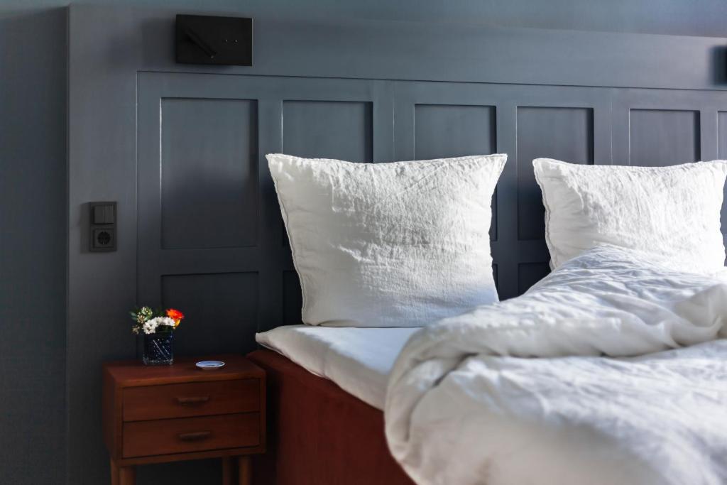 1 dormitorio con 2 camas con almohadas blancas y mesita de noche en Hotel Die Reederin, en Lübeck