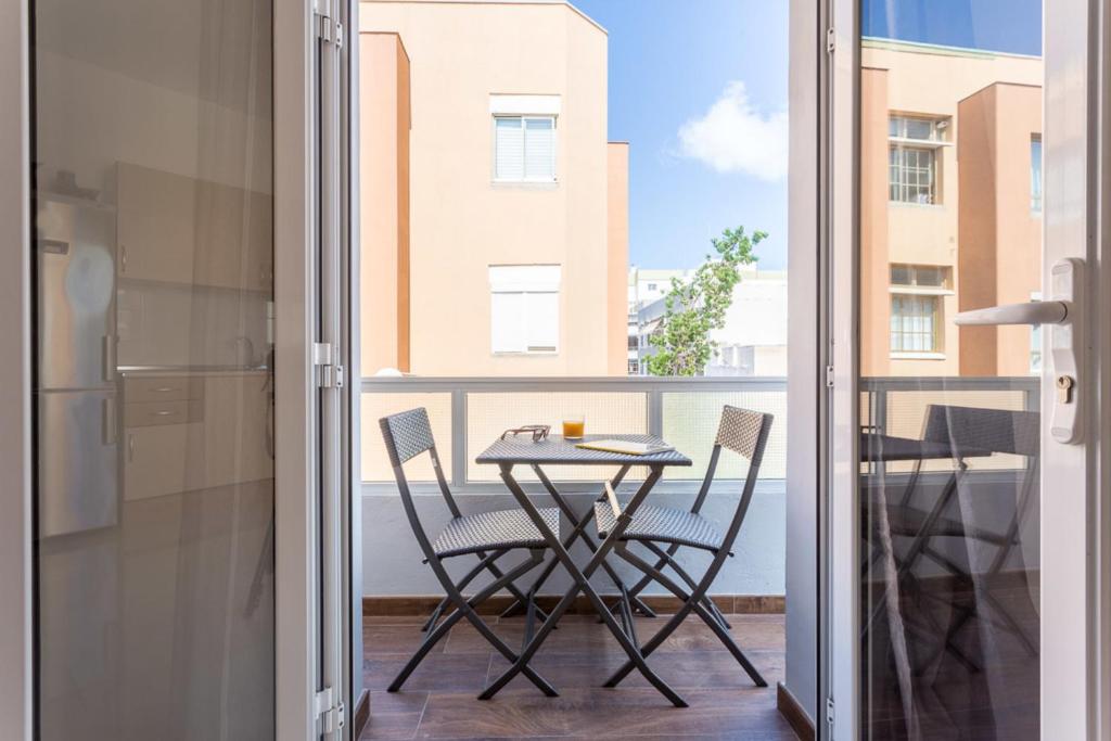 ラスパルマス・デ・グランカナリアにあるBright with terrace next to the beachの建物の景色を望むバルコニー(テーブル、椅子付)