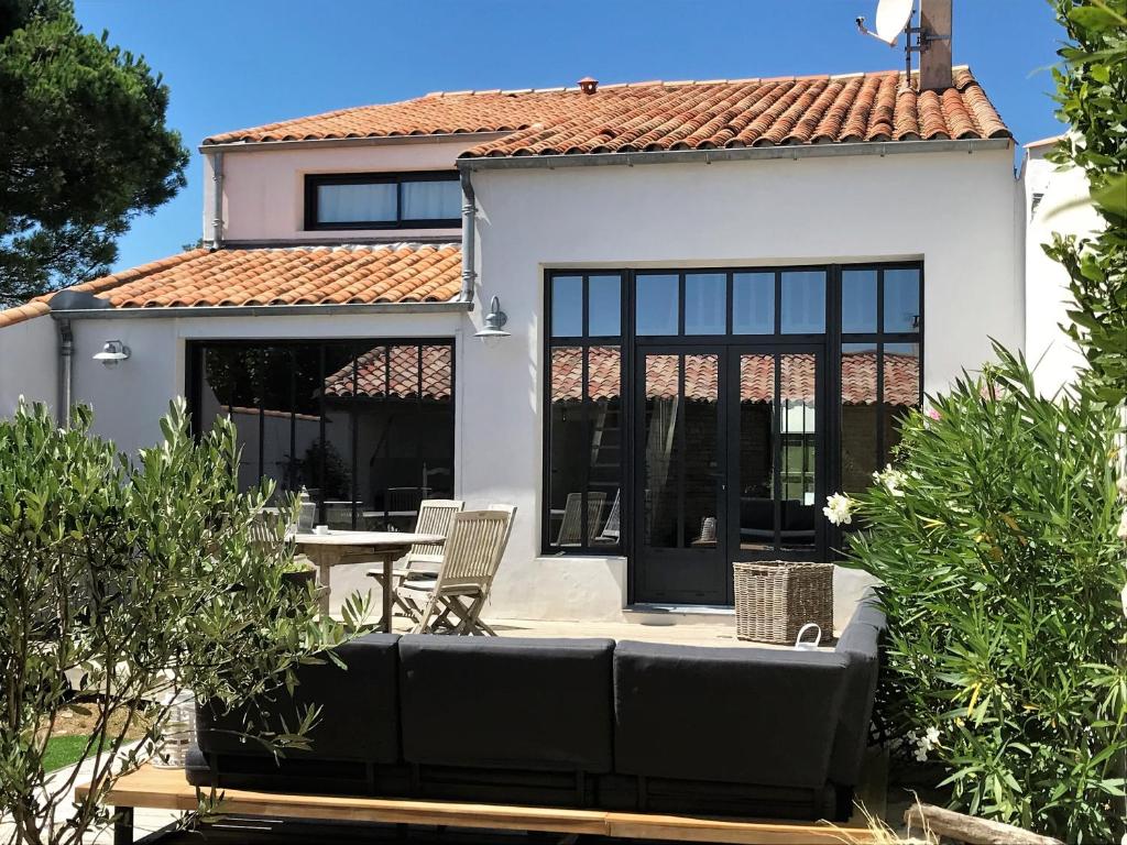 a white house with black windows and a patio at Villa Pigouille in Sainte-Marie-de-Ré