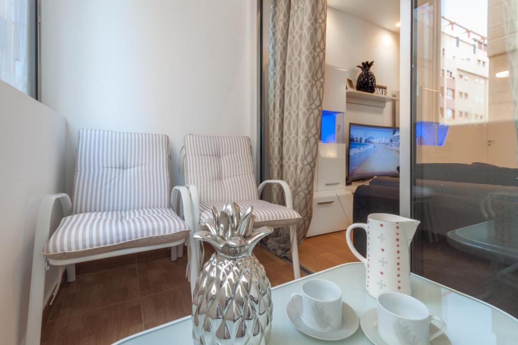ラスパルマス・デ・グランカナリアにあるSpacious Apartment in a Residential areaのリビングルーム(花瓶と椅子付きのテーブル付)