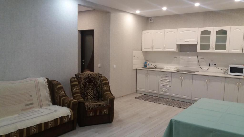 una cocina con armarios blancos, una silla y una mesa en Будинок для гостей по вул. Шевченка, en Beregovo