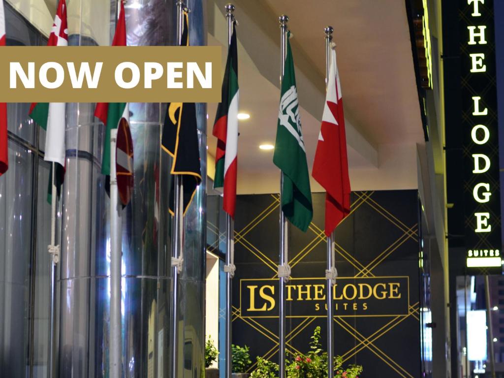 a row of flags in a building with the words now open is the lobby at The Lodge Suites in Manama