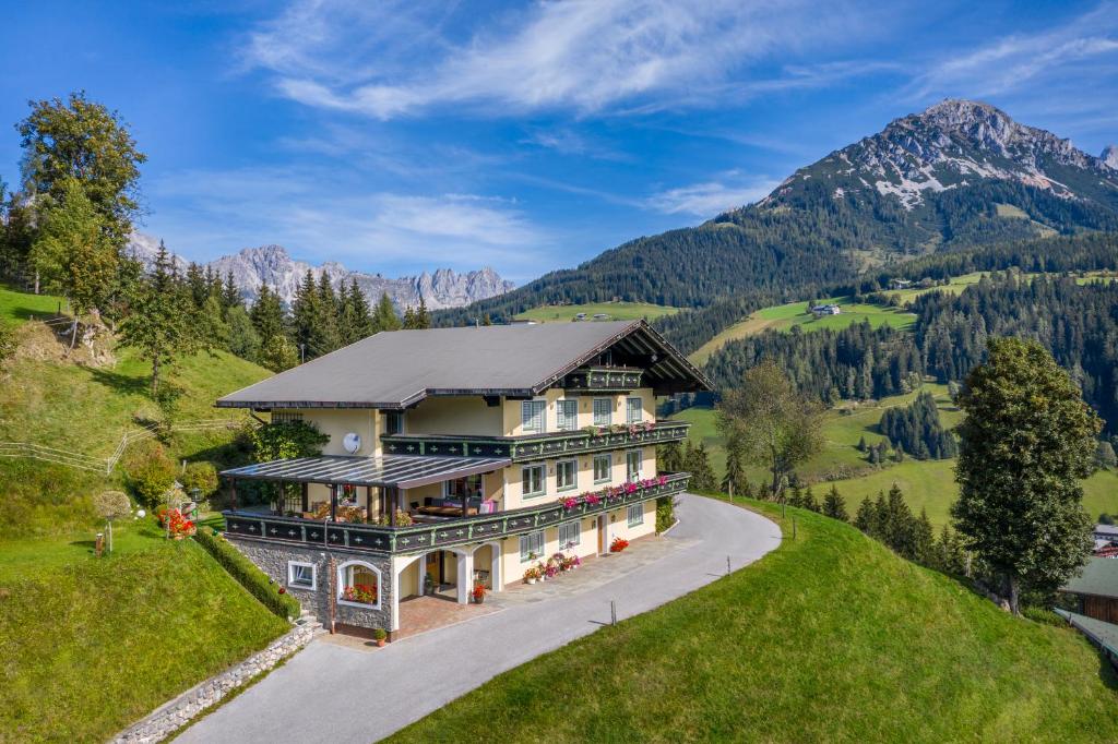 ein Haus auf einem Hügel mit Bergen im Hintergrund in der Unterkunft Haus Kleinberg in Filzmoos