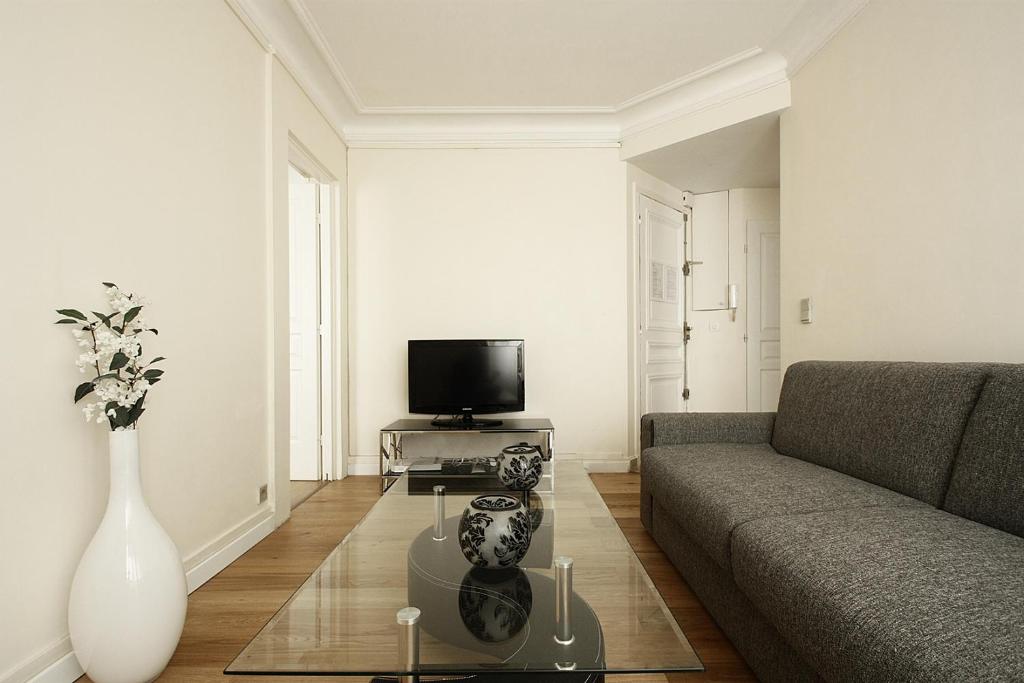 ein Wohnzimmer mit einem Sofa und einem TV in der Unterkunft Bridgestreet Champs-Elysées in Paris