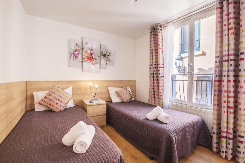 two beds in a room with a window at Hotel De L'Horloge in Paris