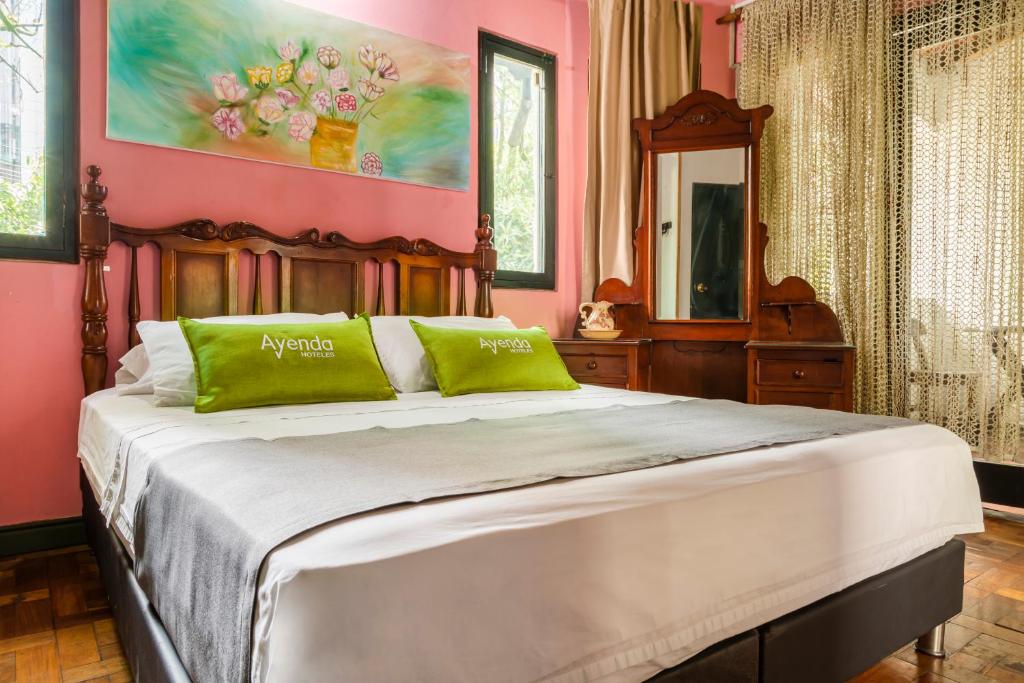 Dormitorio rosa con cama grande con almohadas verdes en Ayenda Habana Vieja 1221, en Medellín