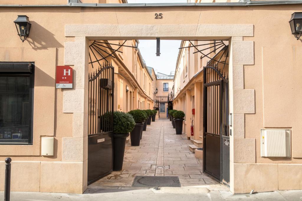 een steegje tussen twee gebouwen met potplanten bij Hotel De L'Horloge in Parijs
