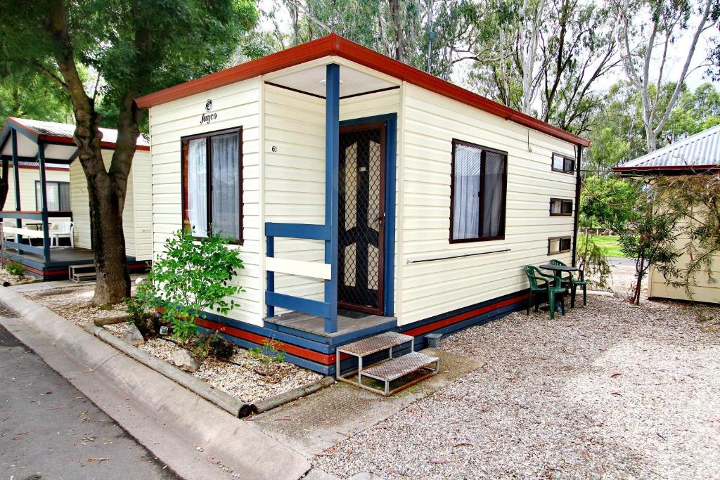 Wangaratta Caravan Park في وانغاراتا: منزل أبيض صغير مع باب وسلالم زرقاء
