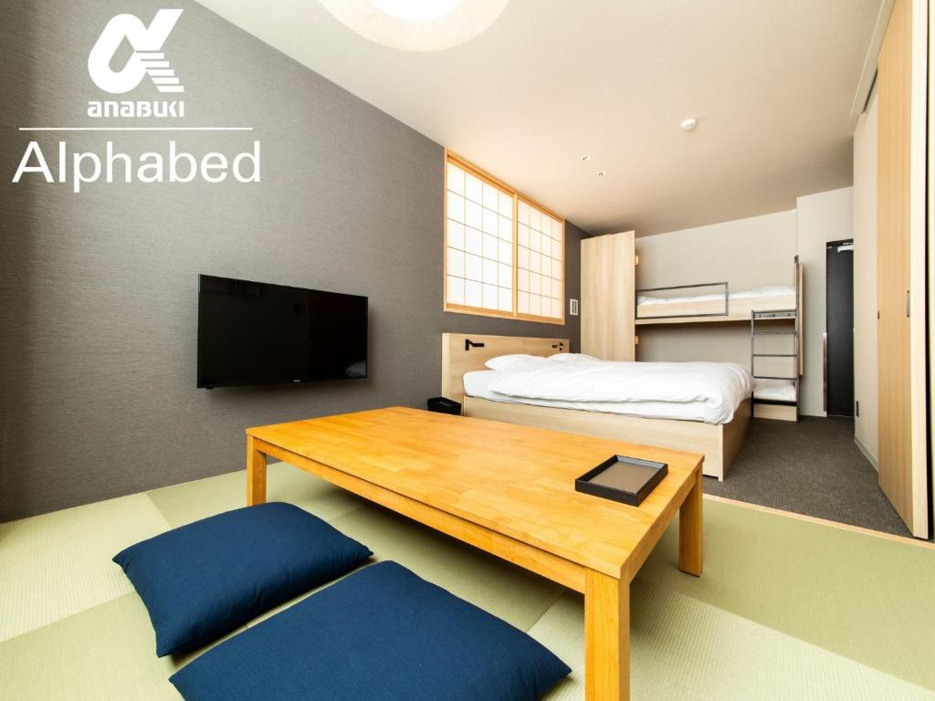 1 dormitorio con cama, mesa y TV en ALPHABED INN Fukuoka Ohori Park - Vacation STAY 06391v en Fukuoka