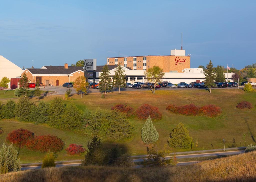 a view of a building and a field with trees at Grand Hotel in Minot