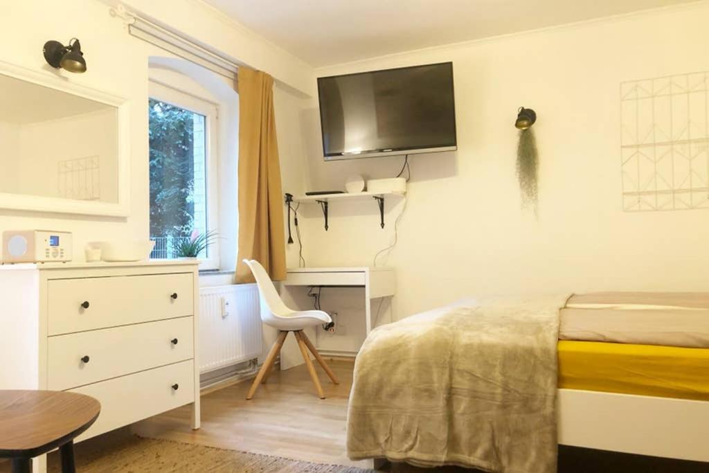 a bedroom with a bed and a desk and a tv at Gemütliche sanierte 1 Zimmer Wohnung mit privatem Parkplatz im Zentrum in Kiel