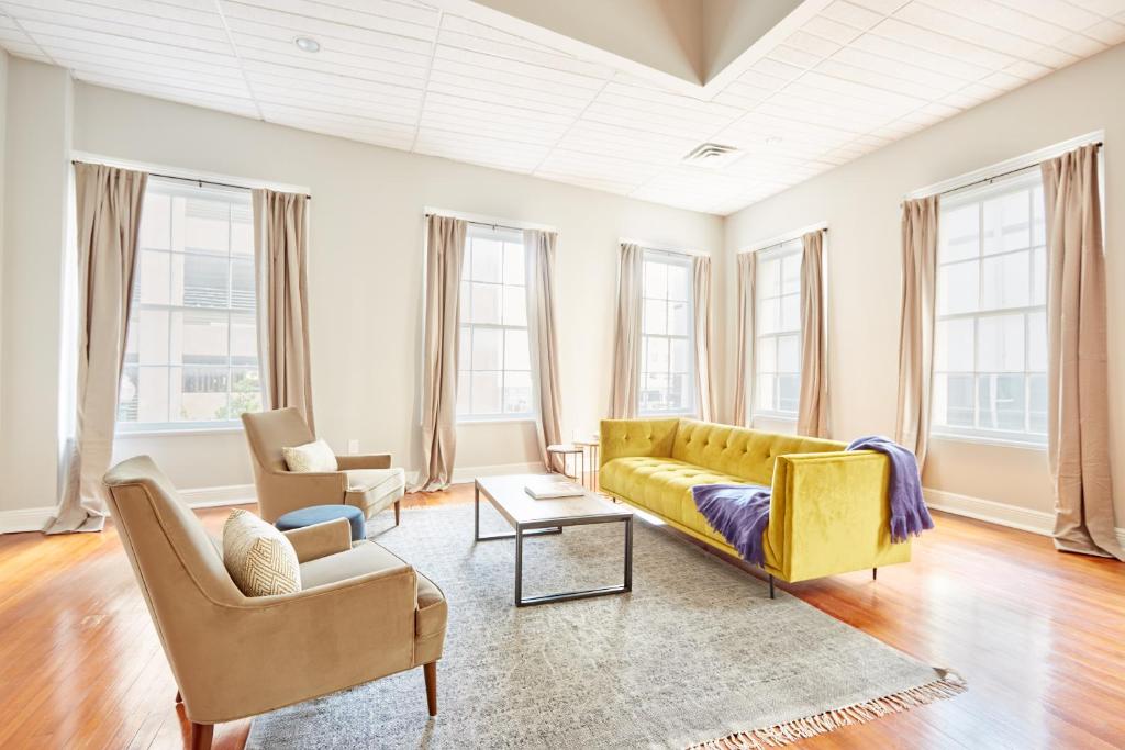 uma sala de estar com um sofá amarelo e cadeiras em Sonder Baronne Manor em Nova Orleans