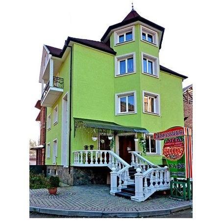 ein großes, grünes Gebäude mit einer weißen Treppe davor in der Unterkunft Садиба Маковиця in Jaremtsche
