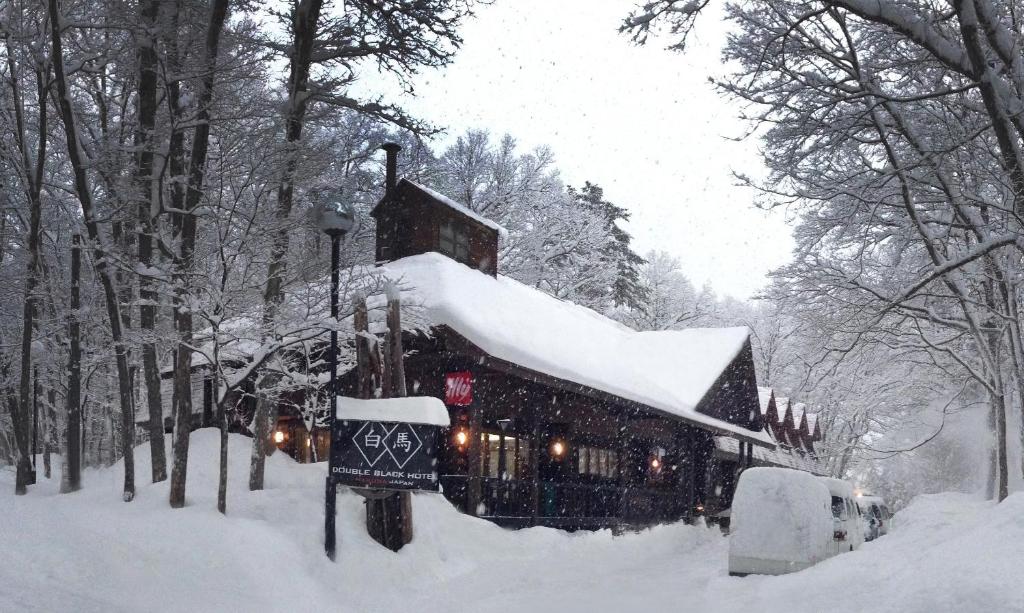 a building covered in snow in a snow storm at Double Black Hotel in Hakuba