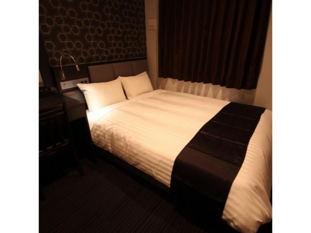 - un lit avec des draps et des oreillers blancs dans l'établissement Hotel Hulaton Fukuokahakata - Vacation STAY 04196v, à Fukuoka