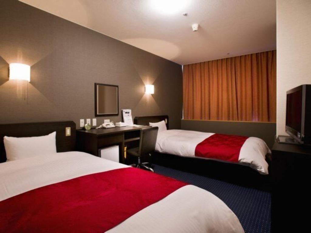 ein Hotelzimmer mit 2 Betten und einem Schreibtisch in der Unterkunft Hotel Taisei Annex - Vacation STAY 05189v in Kagoshima
