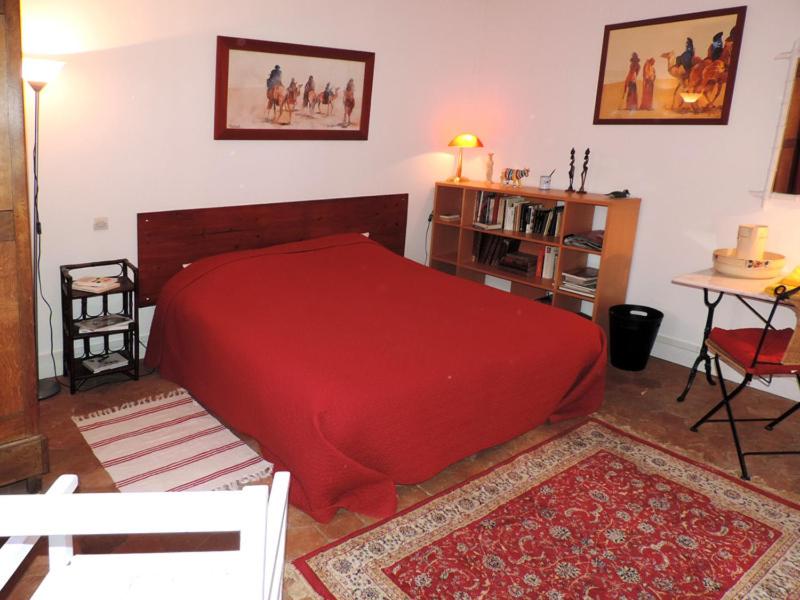 Un dormitorio con una gran cama roja y una mesa en Chambre d'Hôtes Rue des Fougères, en Louviers