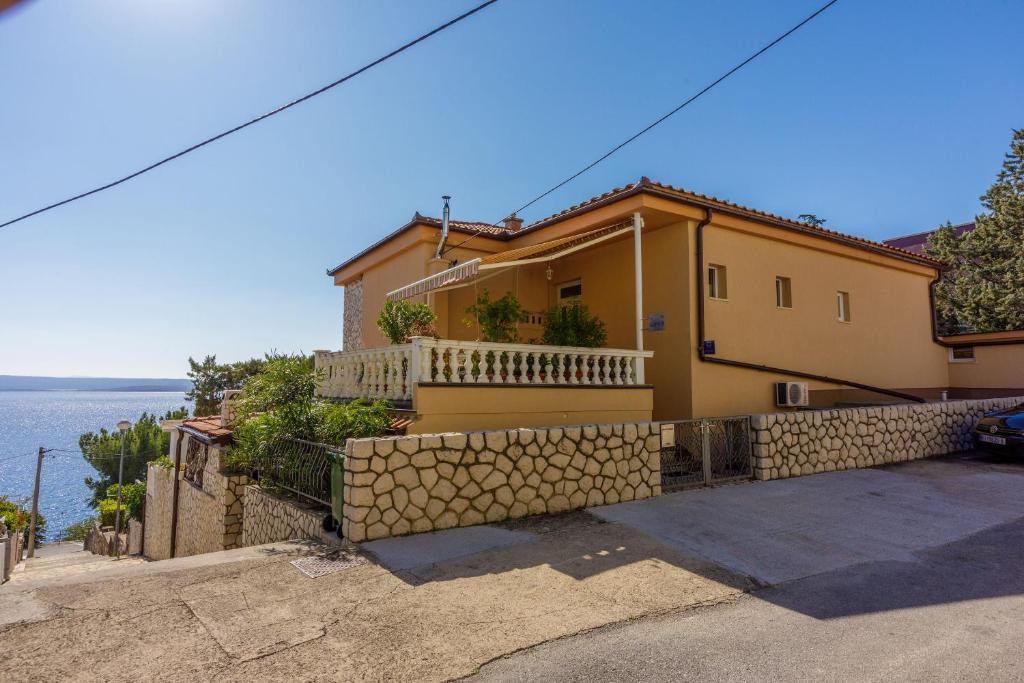 a yellow house with a stone retaining wall at Apartments SENKA in Dramalj