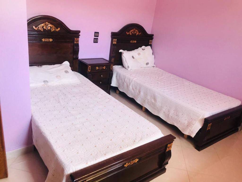 - 2 lits dans une chambre aux murs violets dans l'établissement شقق مفروشة للايجار, à Ksar Sghir