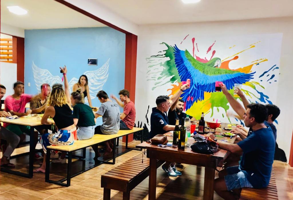 a group of people sitting at tables with their hands in the air at Hostel Park Iguazu in Puerto Iguazú
