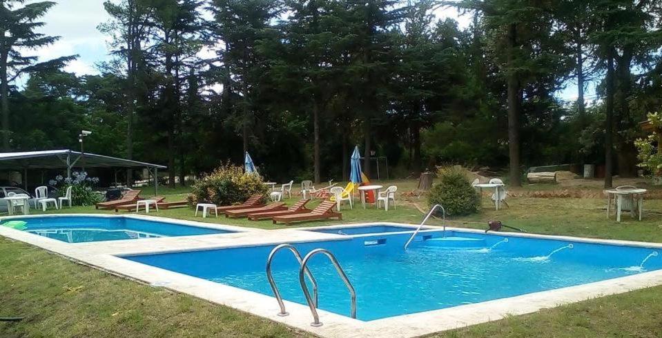 una piscina en un patio con mesas y sillas en Cabañas Alvear en Huerta Grande