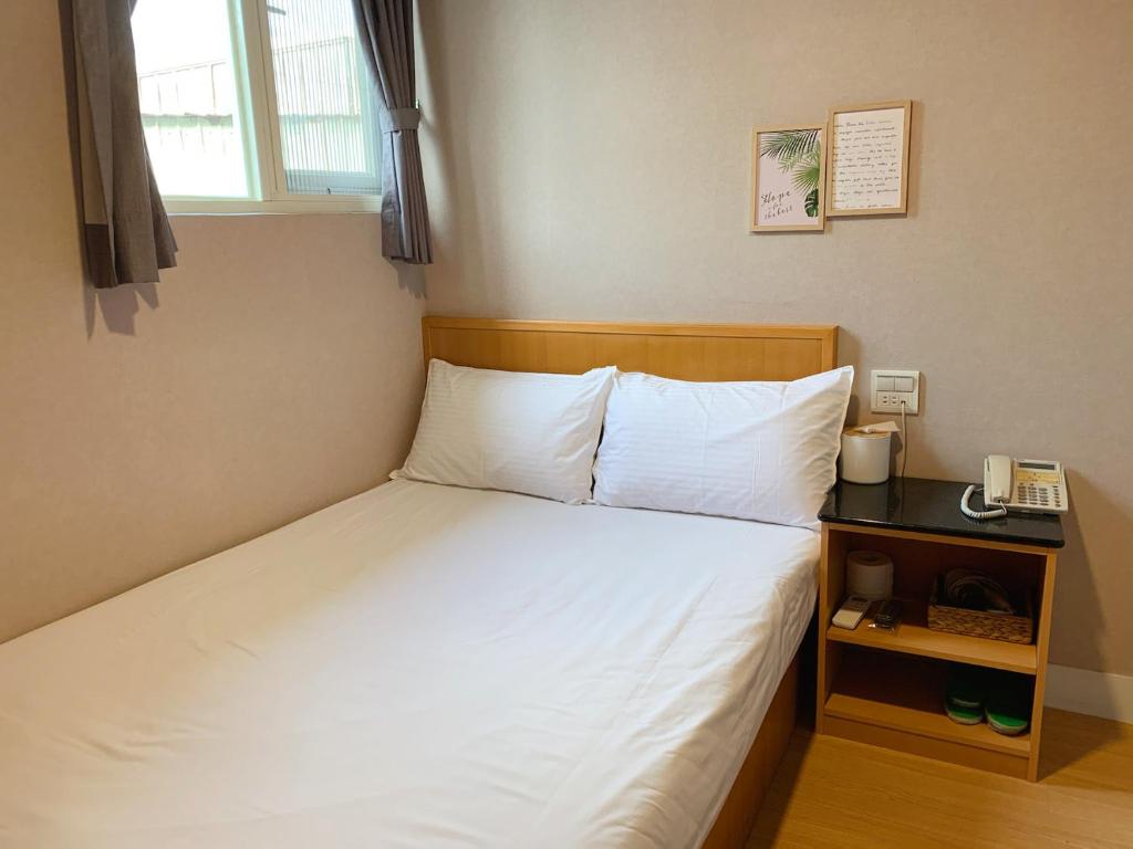 een bed in een kamer met een telefoon op een tafel bij XDZ Hotel in Taipei