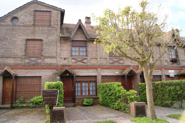 ein großes Backsteinhaus mit einem Baum davor in der Unterkunft De Las Artes XII - triplex sólo familias in Pinamar