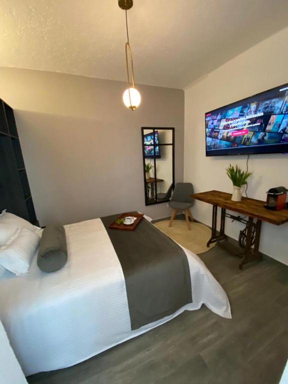 a bedroom with a bed and a desk and a tv at Siete Puertas Coyoacán in Mexico City